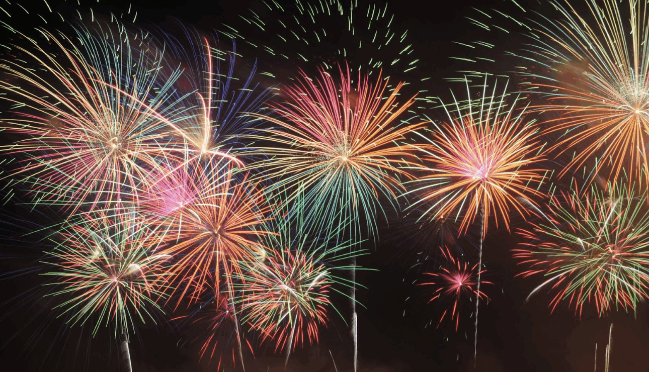夜空中同時綻放的多個彩色放射狀煙火，包含紅、綠、黃、紫等鮮艷色調。