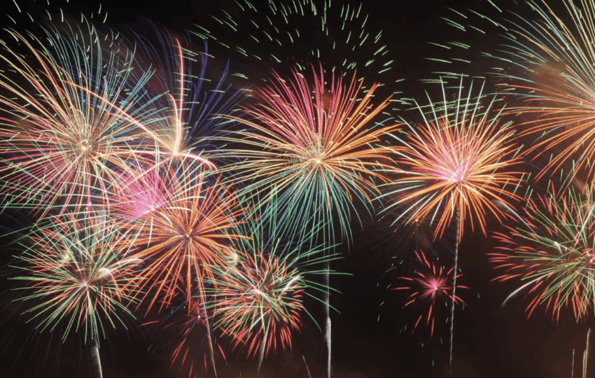夜空中同時綻放的多個彩色放射狀煙火，包含紅、綠、黃、紫等鮮艷色調。
