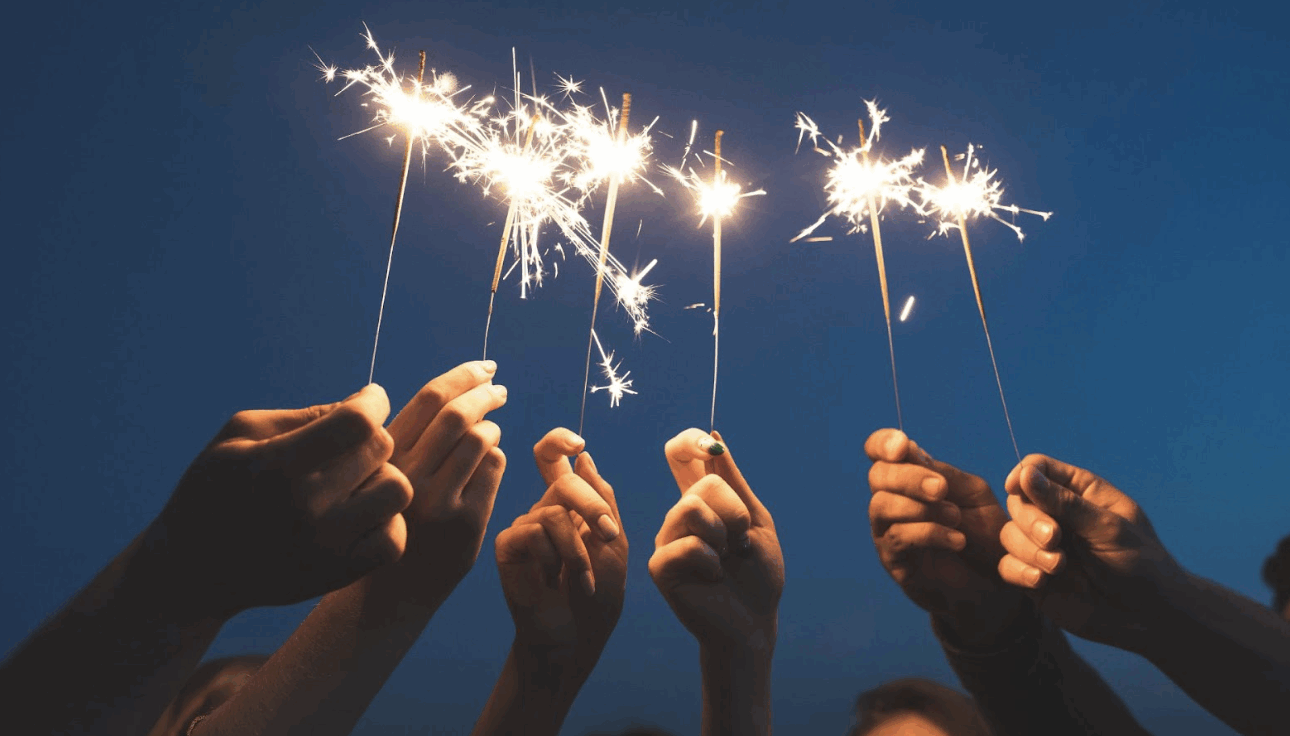 多人手持點燃的仙女棒煙火，在深藍色傍晚夜空下營造浪漫歡樂的慶祝氛圍，適合作為節慶、派對或友誼主題視覺。