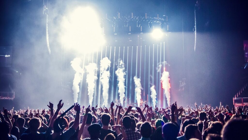 室內演唱會高潮時刻，舞台上數根白色乾冰煙霧柱升起，配合強烈的聚光燈投射，現場群眾情緒高漲